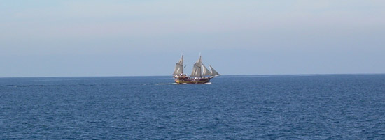 Barco de vela en alta mar sobre el inmeso cielo azul